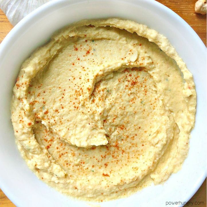 overhead shot of a white bowl filled with oil-free and tahini-free hummus, sprinkled with smoked paprika