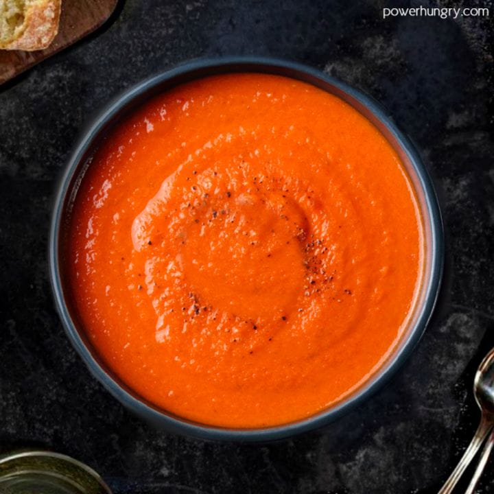overhead shot of 3-ingredient tomato lentil soup in a dark bowl on top of a slate board