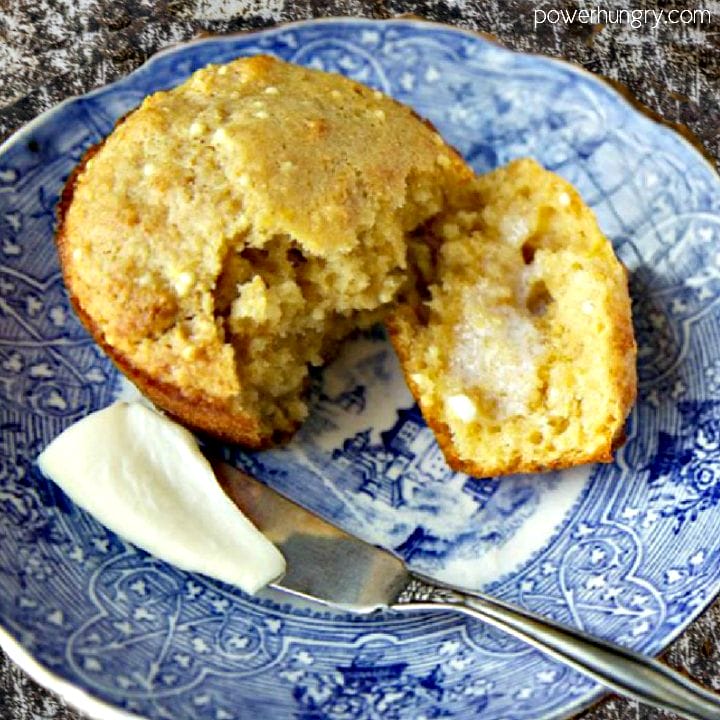 Banana millet muffin on a blue and white plate, split opne and spread with vegan butter