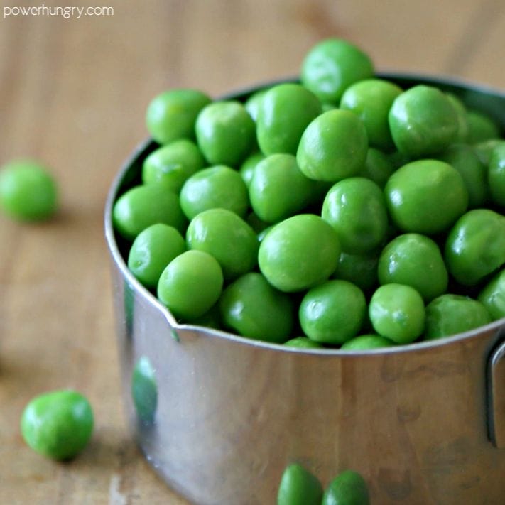 frozne thawed green peas in a measuring cup