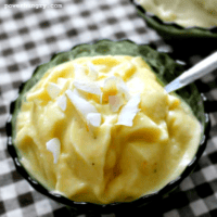banana mango coconut ice cream in a green dish topped with coconut flakes