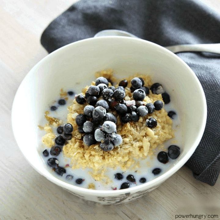 overnight brown rice porridge, made in a slow cooker, in a white bowl topped with milk, walnuts and blueberries