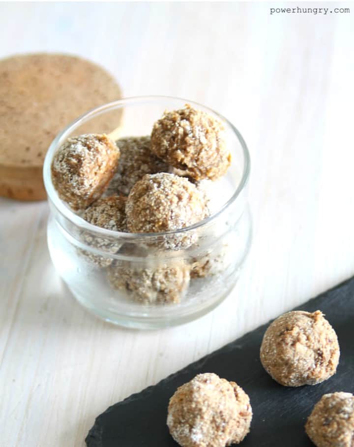 Almond Butter Coconut Flour balls in a glass jar, with more balls on a piece of black slate