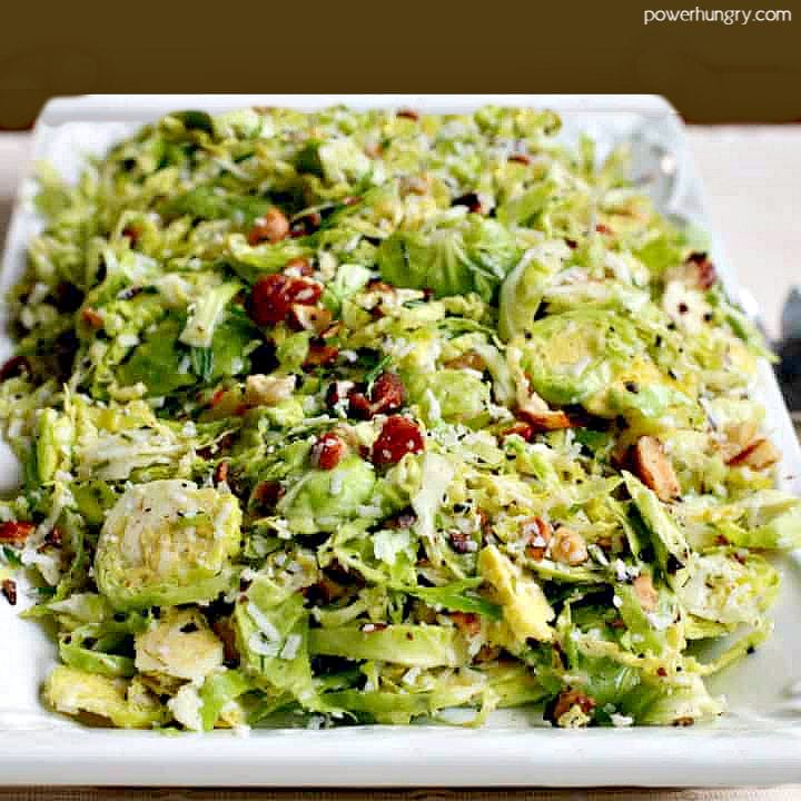 lemony shredded brussels sprouts salad on a white dish atop a white linen napkin