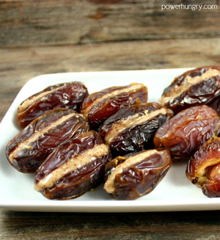 medjool dates stuffed with almond butter , sitting on a white plate