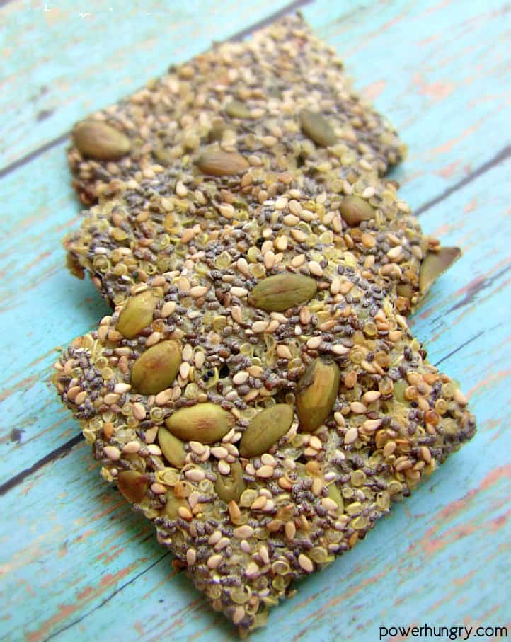 3 multi-seed quinoa crackers on a piece of blue painted wood