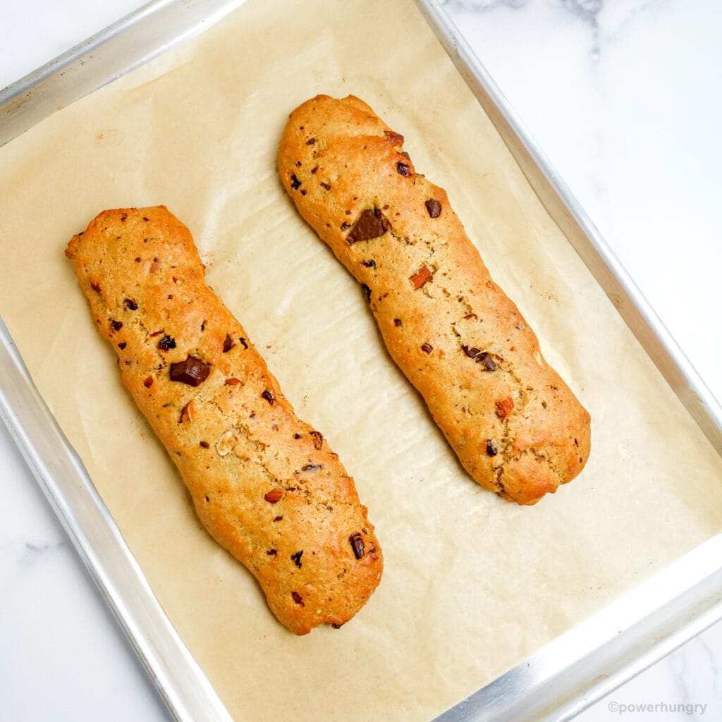 two baked biscotti logs on a parchment lined baking sheet
