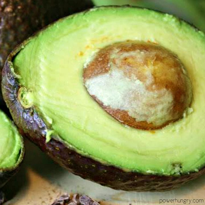 close up of and avocado, halved, on a cutting board