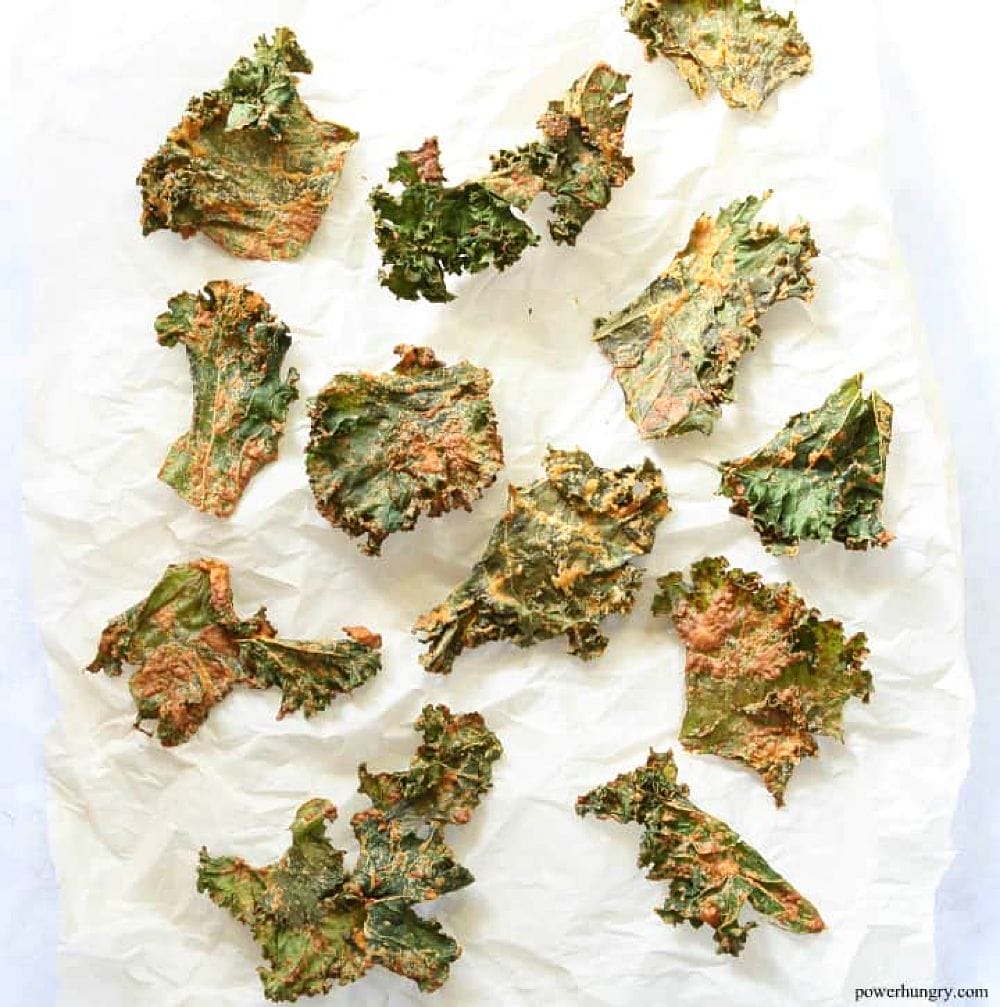 coated kale chips on white parchment paper