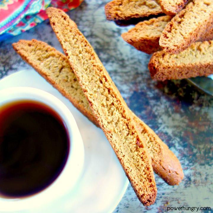 2 chcikpea flour biscotti with a cup of coffee and colorful napkin
