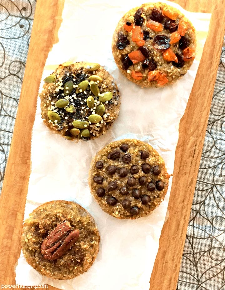 overhead shot of 3-ingredient banana quinoa muffins on a piece of parchment paper, atop a cutting board, with assorted toppings