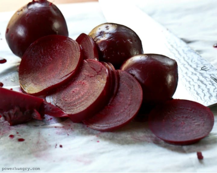 roasted beets, some of which are sliced, atop a piece of parchment paper