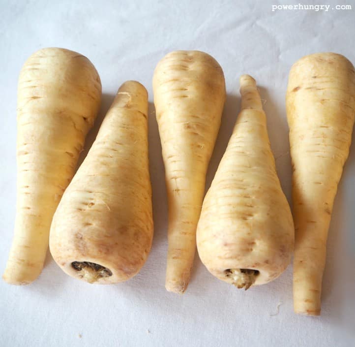 raw parsnips on a piece of parchment paper.