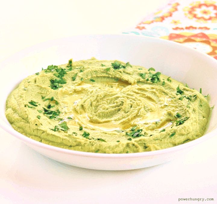 broccoli hummus in a white bowl with a colorful napkin in the background