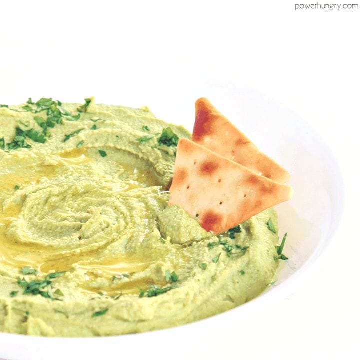 healthy broccoli hummus in a white serving bowl with some healthy chips