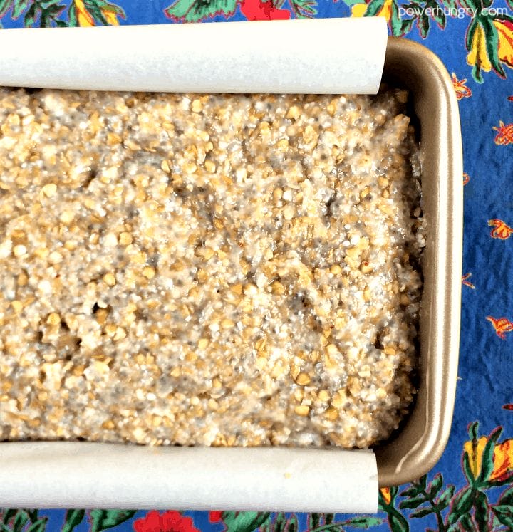 overhead shot of buckwheat flax chia bread batter in a small loaf pan, a blue napkin in the background