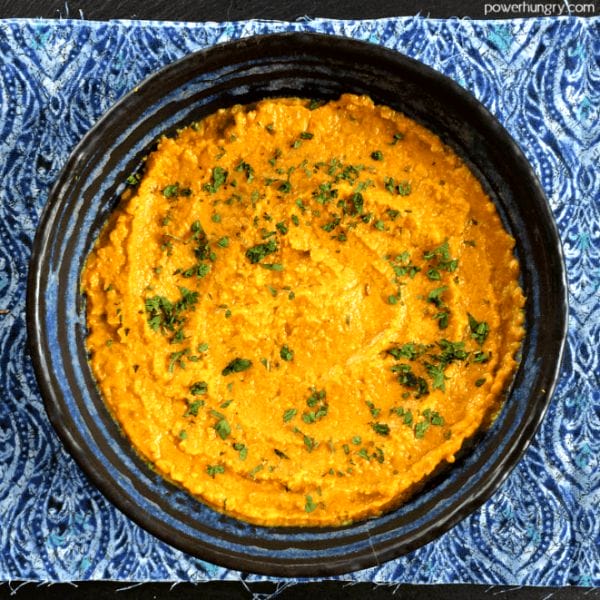 red lentil daal spread in a blue pottery bowl atop a blue patterned napkin