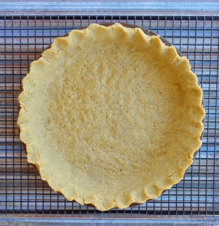 Overhead shot of baked chickpea flour pie crust on black cooling rack