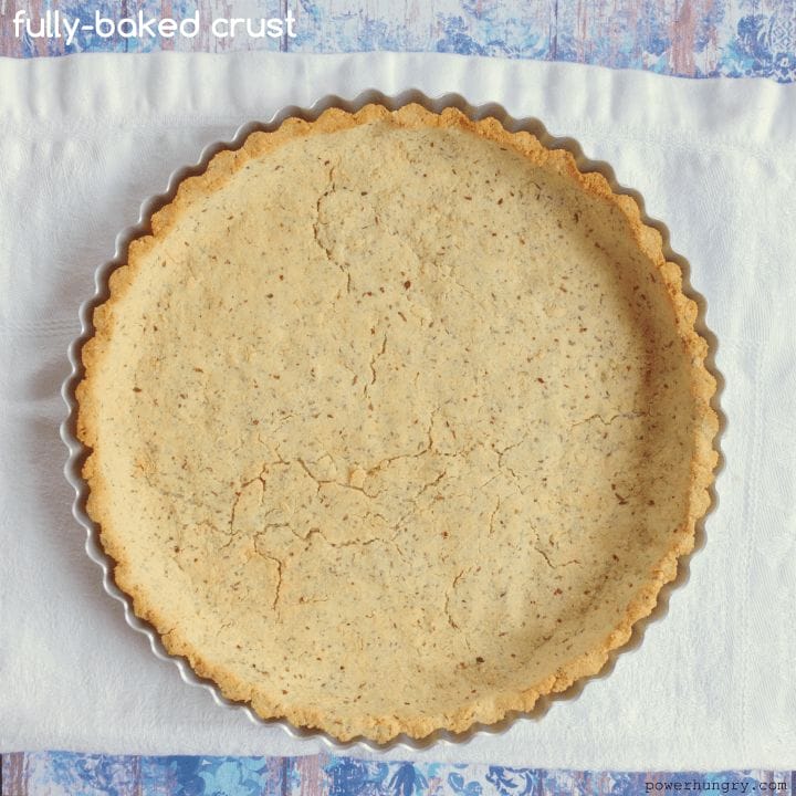 baked coconut-almond flour pie crust on a piece of white parchment paper
