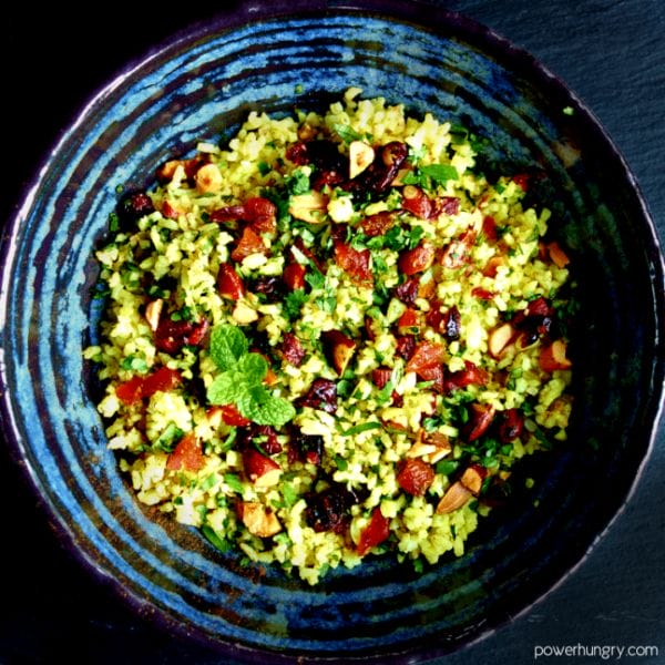 jeweled cauliflower rice in a blue pottery bowl with a black background