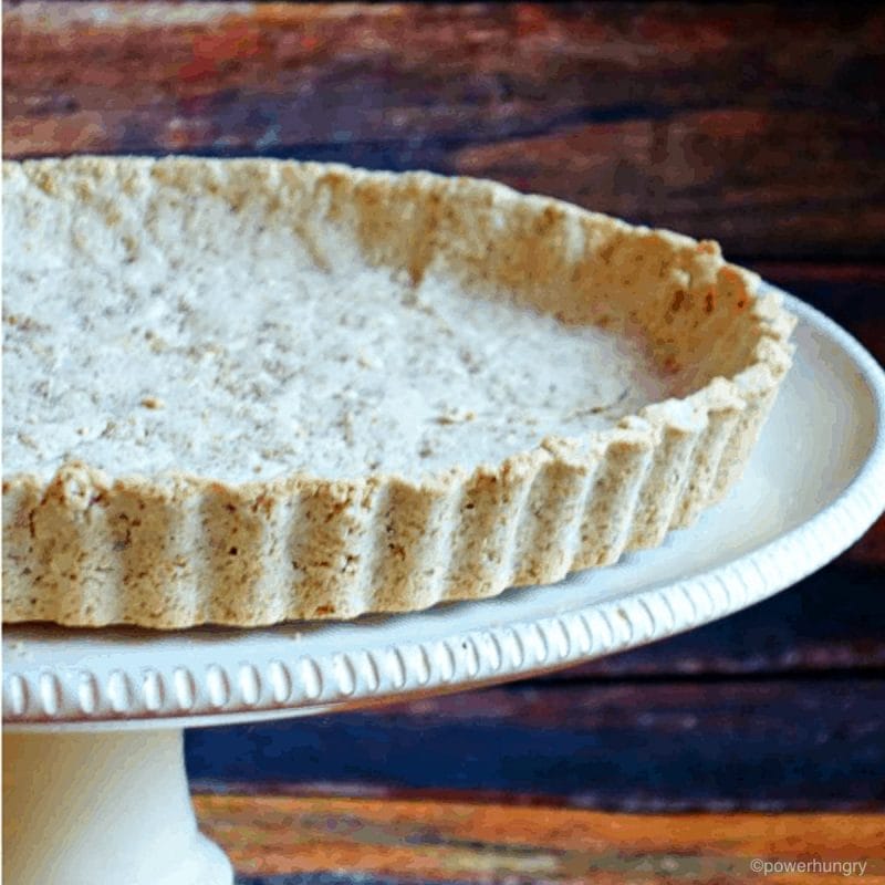 tiger nut flour pie curst on an off-white cake pedestal
