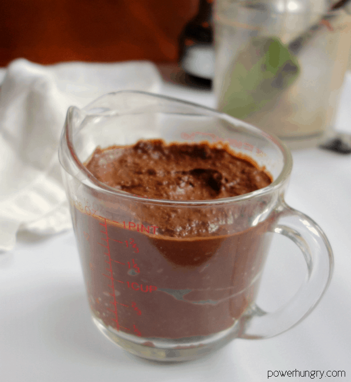 glass measuring cup filled with brownie batter hummus