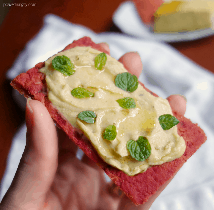 hummus spread on a piece of chickpea flour and beet flatbread