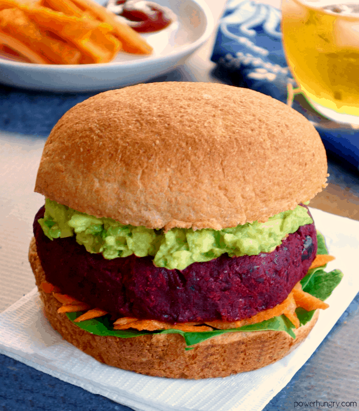 Vegan beet burger on a bun with mashed avocado and vegetables