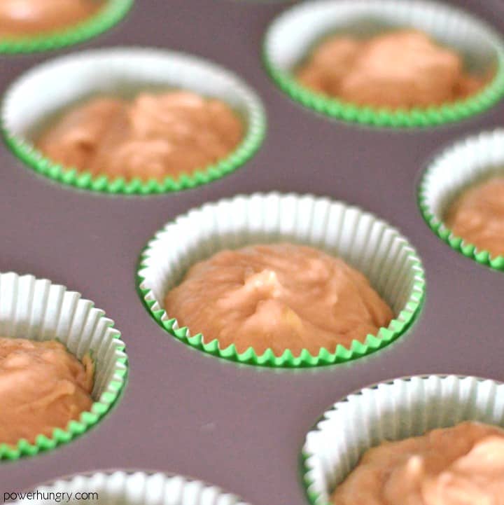 muffin tin , lined with green paper liners, file with chickpea flour muffin batter