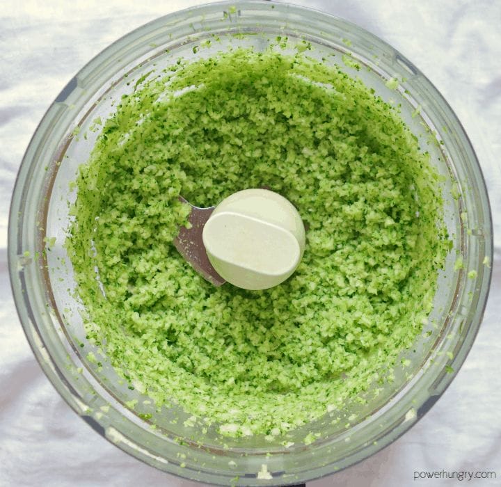 overhead shot of a food processor bowl filled with finely chopped broccoli