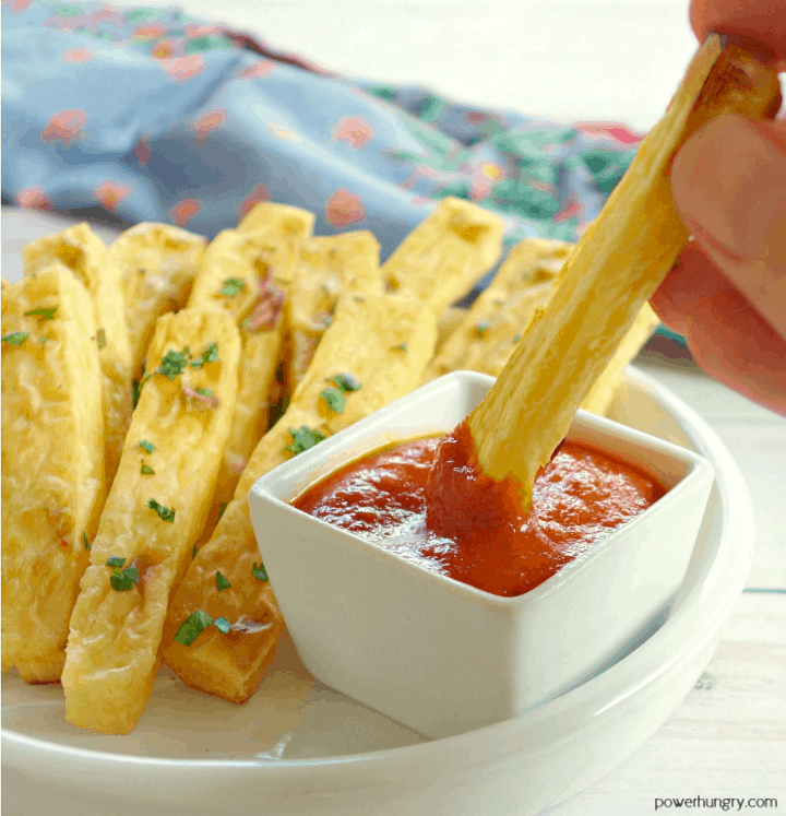 chickpea flour French fries, with one fry being dipped into a small container of ketchup