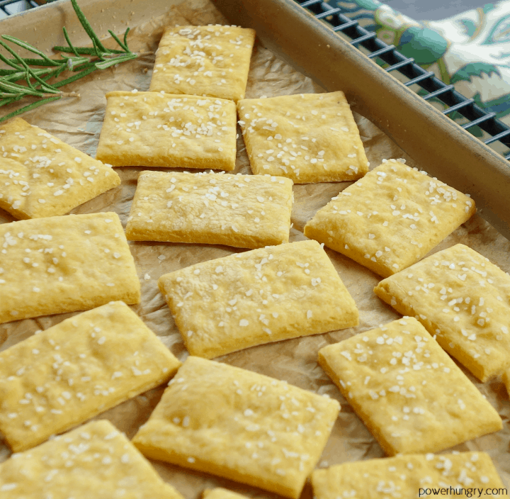 cheese-y chickpea flour crackers topped with sea salt on a pottery baking sheet lined with parchment paper.