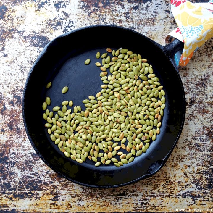 toasted pepitas in a black cast iron skillet