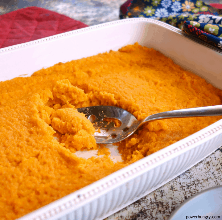 Vegan carrot soufflé in a cream-colored serving dish, a floral napkin in the background