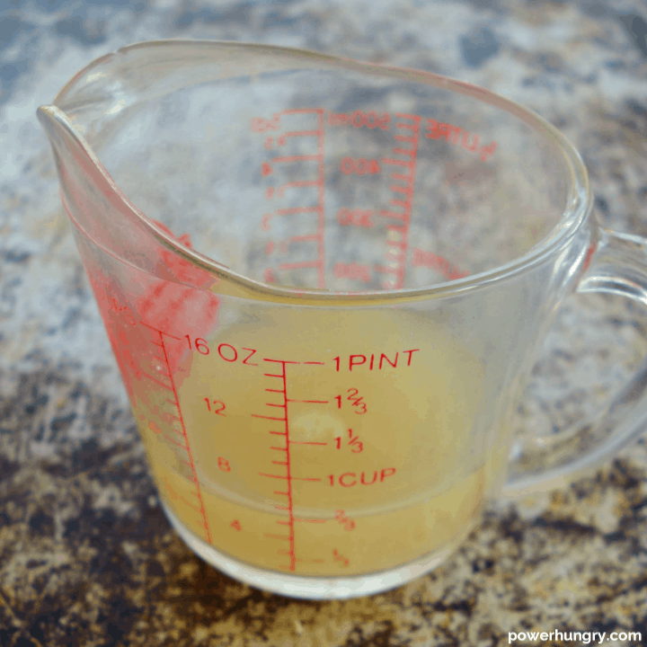 a glass measuring cup filled with aquafaba (chickpea liquid)