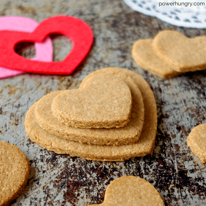 2-ingredient almond flour cut out cookies in the shape of hearts on an aged metal background