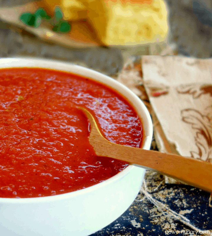 close-up of 3-ingredient tomato soup in a white bowl with a wooden spoon