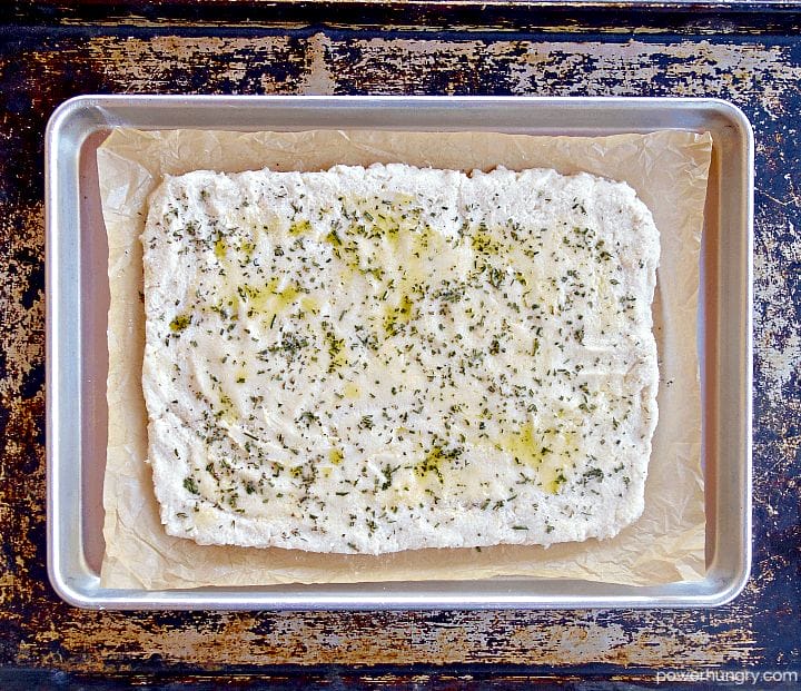 unbaked white bean flatbread on a parchment paper-lined baking sheet