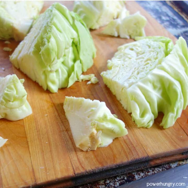 cabbage pieces on a wooden cutting board with the cores being cut out