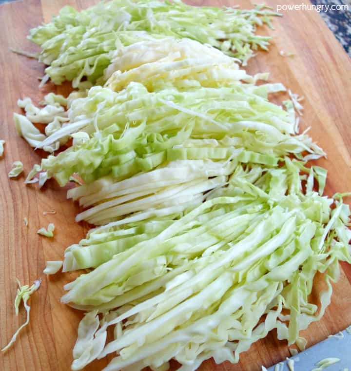 thinly sliced cabbage on a wood cutting board