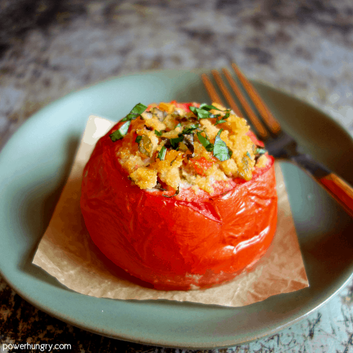 Stuffed tomato, made with coconut flour, on a piece of parchment paper on an olive colored plate
