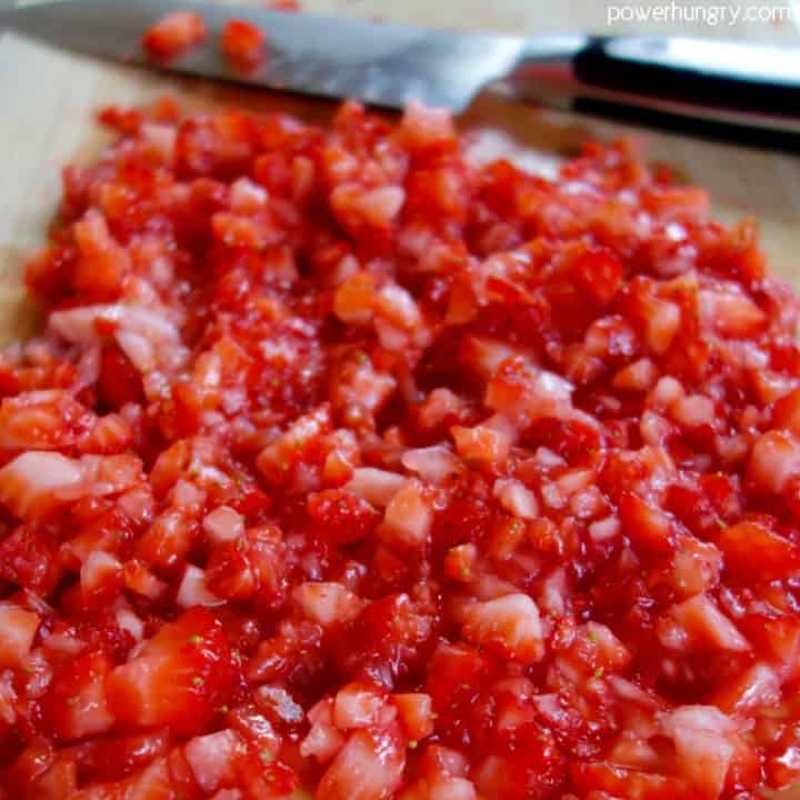 Chopped fresh strawberries spread in a parchment paper lined baking pan