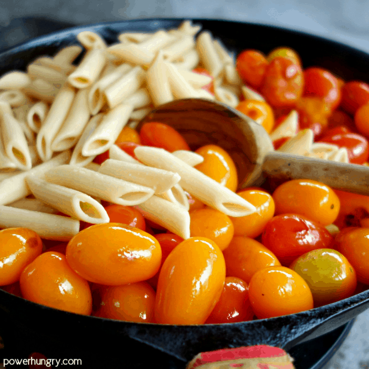 sauteed cherry tomatoes and chickpea pasta in a cast iron skillet