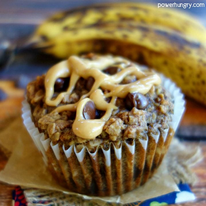 Peanut Butter Banana Baked Oatmeal Cup on a piece of parchment paper with bananas in the background