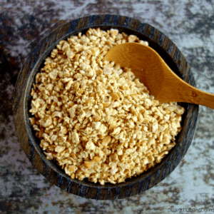 dark wooden bowl filled with chickpea breadcrumbs, with a wooden spoon inserted into crumbs