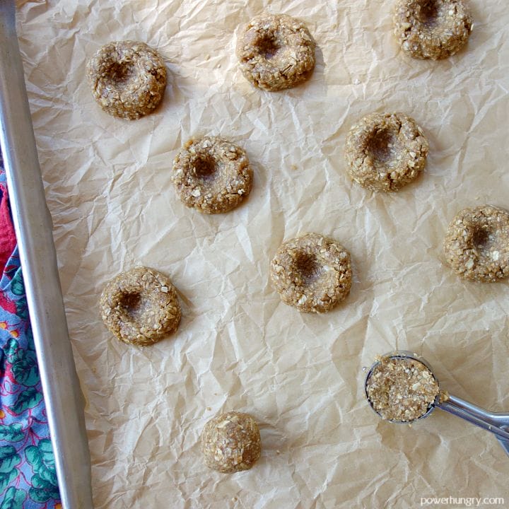 vegan oat cookie dough being scooped and shaped onto a parchment paper-lined baking sheet