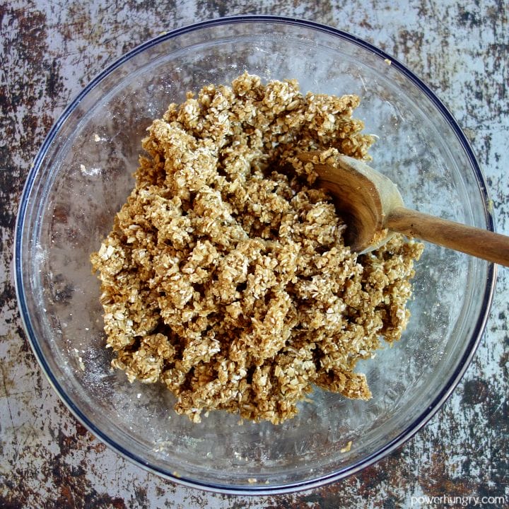 cookie dough for the vegan oat thumbprints in a glass bowl with a wooden spoon