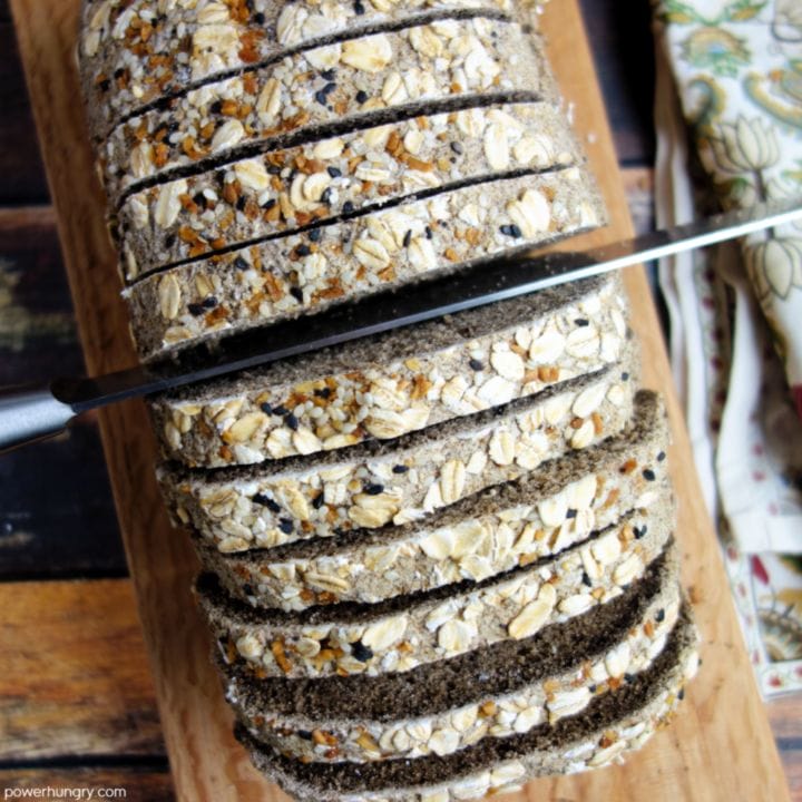 overhead shot of buckwheat bread being sliced with a serrated knife