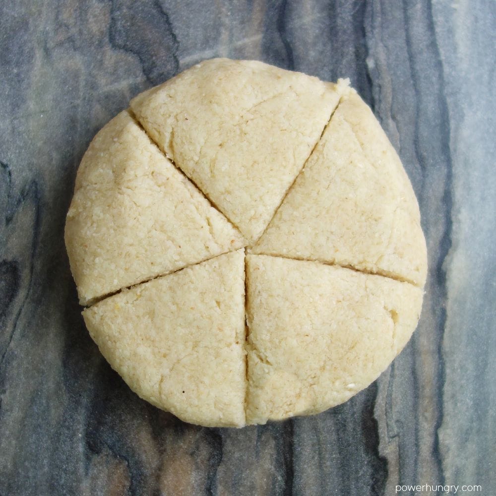 almond flour tortilla dough on a cutting board, cut into 5 equal pieces