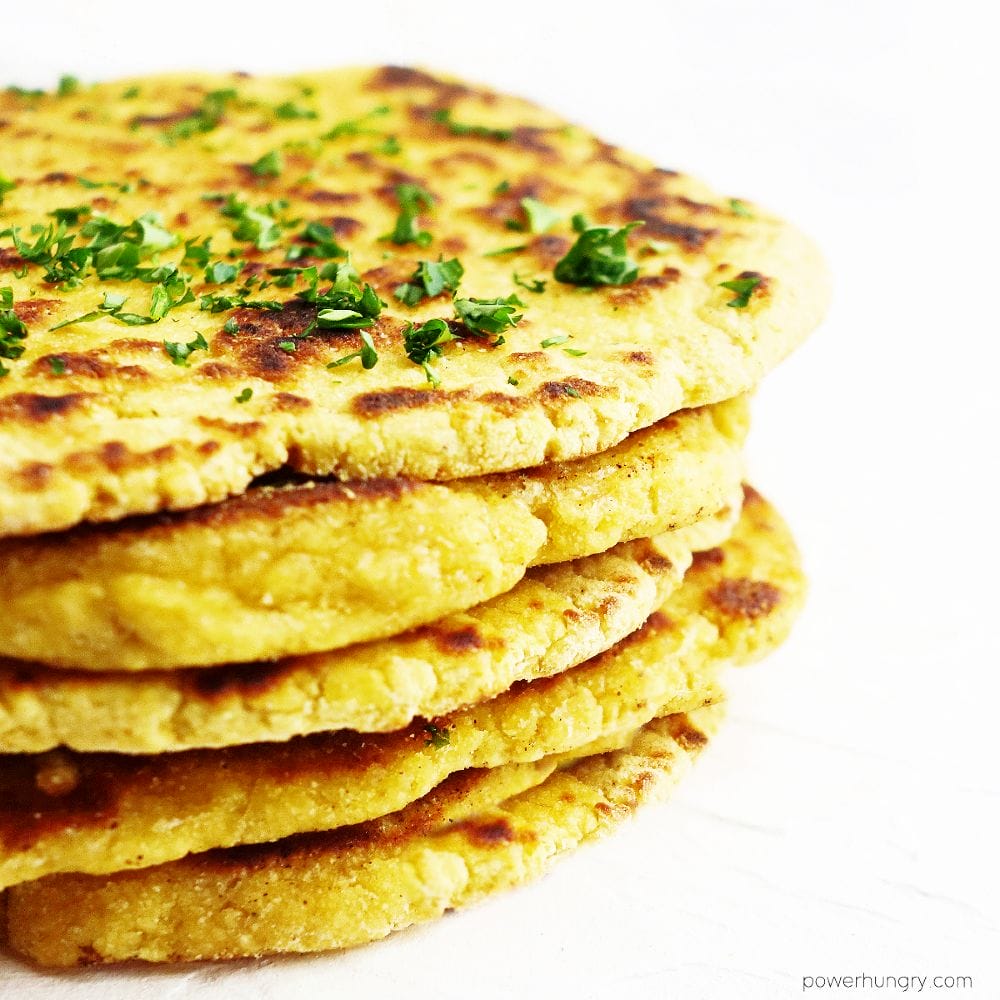 stack of chickpea flour naan sprinkled with finely chopped parsely 